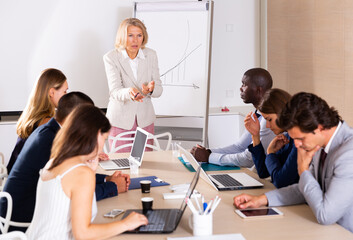 Fototapeta premium Unhappy business woman blaming subordinates for bad work on staff meeting at office