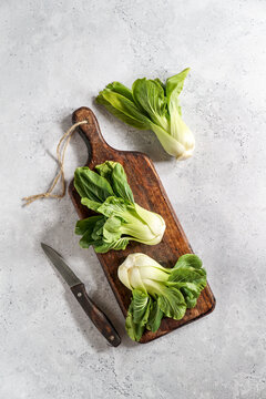 Fresh Bok Choy or Pak Choi (Chinese cabbage) on the dark wooden cutting board on stone background, organic vegetables