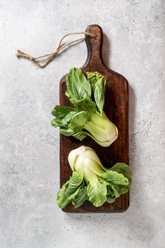Fresh Bok Choy or Pak Choi (Chinese cabbage) on the dark wooden cutting board on stone background, organic vegetables