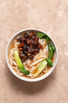 Aubergine pho with pak choi in a ceramic bowl.