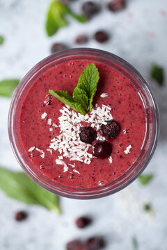 A blackcurrant smoothie garnished with blackcurrants, mint and desiccated coconut.