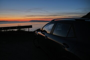 Black car parked on a coast at sunset - Powered by Adobe