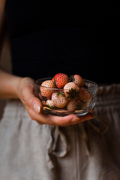 Hand holding a bowl of pineberries