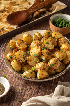 Bowl of baked herb potatoes with wood spoons
