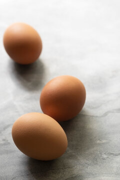 Three brown chicken eggs on a textured background.