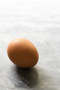 A chicken egg on light grey marble.