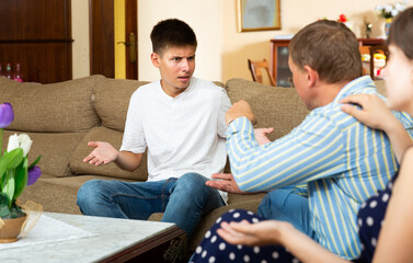 Angry parents scolding their sad young son in living room