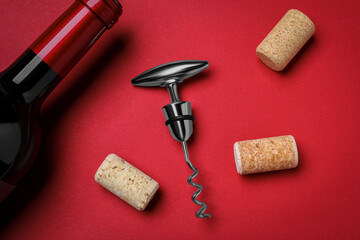 Corkscrew with wine bottle and stoppers on red background, flat lay
