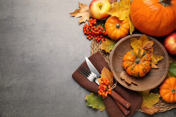 Flat lay composition with tableware, autumn leaves and vegetables on grey background, space for...