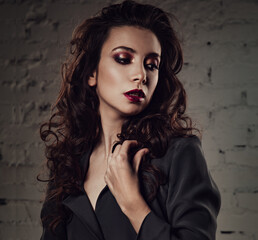 Beautiful bright makeup woman with long black curly hair style posing in silver elegant dress suit,...