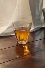 Hot tea cup on wooden table near white curtain window with nature sunlight in the morning.