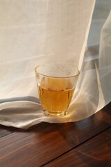 Hot tea cup on wooden table near white curtain window with nature sunlight in the morning.