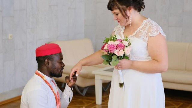 An African groom put a ring on the finger of a Caucasian bride during the wedding ceremony. interracial wedding