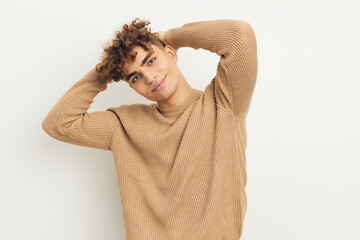 a cute, stylish, curly-haired man stands on a light background looking pleasantly at the camera, in...