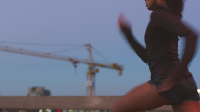 Woman running for fitness motivation in urban city, training for a marathon competition at night and doing cardio for strong and healthy body on dark road. Sprinter sprinting fast and with speed