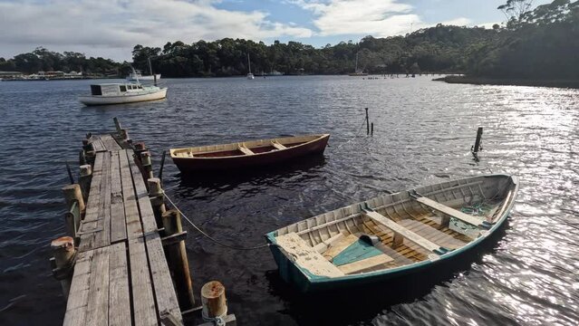 Rowing boats floating next to a wooden pier in Strahan, West Coast of Tasmania