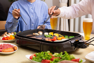 ビールを飲みながら焼肉を食べる家族