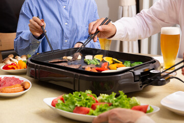 ビールを飲みながら焼肉を食べる家族