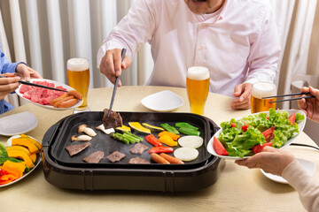 ビールを飲みながら焼肉を食べる家族