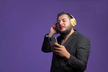 non-binary person in a smart suit listening to music with his smartphone and headphones on an...
