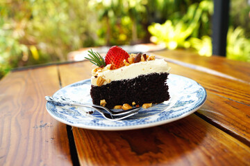 Dark beer chocolate cake garnished with cream cheese, strawberries, rosemary, nuts.             