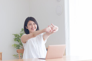 パソコンの前で伸びをする女性