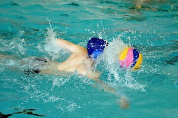 Young men play water polo in a swimming pool 