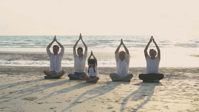 Holiday concept of 4k Resolution. Everyone in the family is doing yoga by the beach. summer vacation travel.