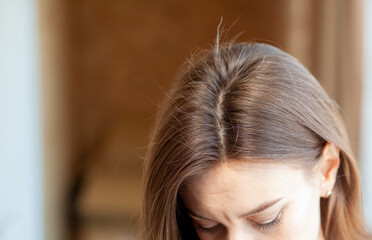 Parting of women's hair on the head. Hair care and care. Closeup of a woman's head with parted gray...