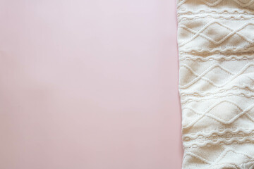 Top view of a white knitted sweater on a pink background.