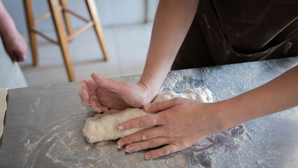 The process of making traditional French baguettes. Forming a blank from the dough. Front view.