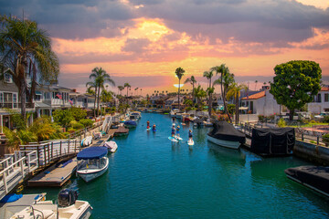 a gorgeous summer landscape at the Naples Canals with boats docked along the banks and people on...