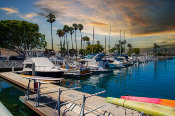 a gorgeous summer landscape in the marina with boats and yachts docked in Alamitos Bay Marina surrounded by lush green palm trees and powerful clouds at sunset in Long Beach California USA