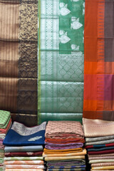 Artistic variety shade tone colors ornaments patterns, closeup view of stacked saris or sarees in...