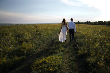 young people walk in an embrace across the field. couple in love