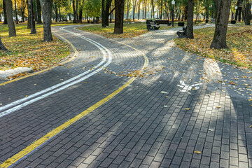 autumn park scenery on sunny day with winding bike lane and footpath