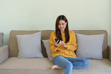 woman sitting on sofa at home ready to use mobile phone