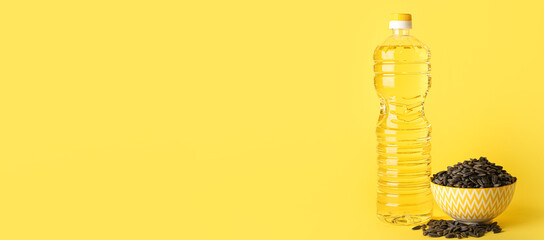 Bottle of sunflower oil and seeds on yellow background with space for text