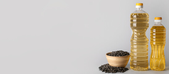 Bottles of sunflower oil and seeds on light background with space for text