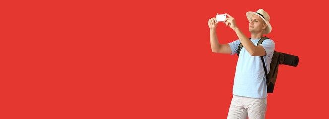 Male tourist taking photo on red background with space for text