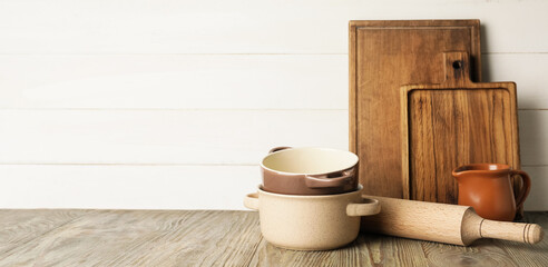 Set of kitchen utensils on table against light background with space for text