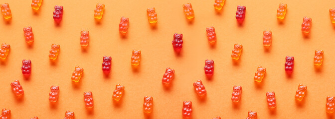 Many sweet jelly bears on orange background, top view