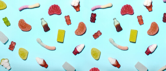 Many sweet jelly candies on light blue background, top view