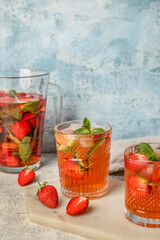 Glasses of strawberry lemonade on table against grunge background