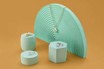 Showcase pedestals with different jewelry on beige background