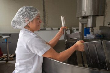 Woman with uniform working in a dairy processing factory