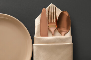 Napkin with cutlery and plate on dark background, closeup
