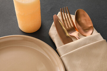 Napkin with cutlery and plate on dark background, closeup