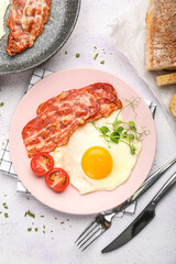 Plate of tasty fried egg with bacon on light table