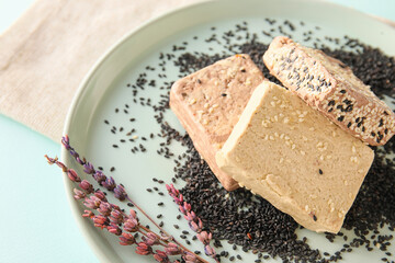Plate with slices of tasty  sesame halva on color background, closeup